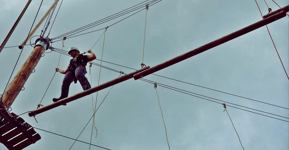 Person, die hoch oben im Hochseilgarten balanciert