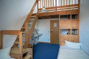 Übernachtungsraum mit Betten, Waschbecken und Treppe